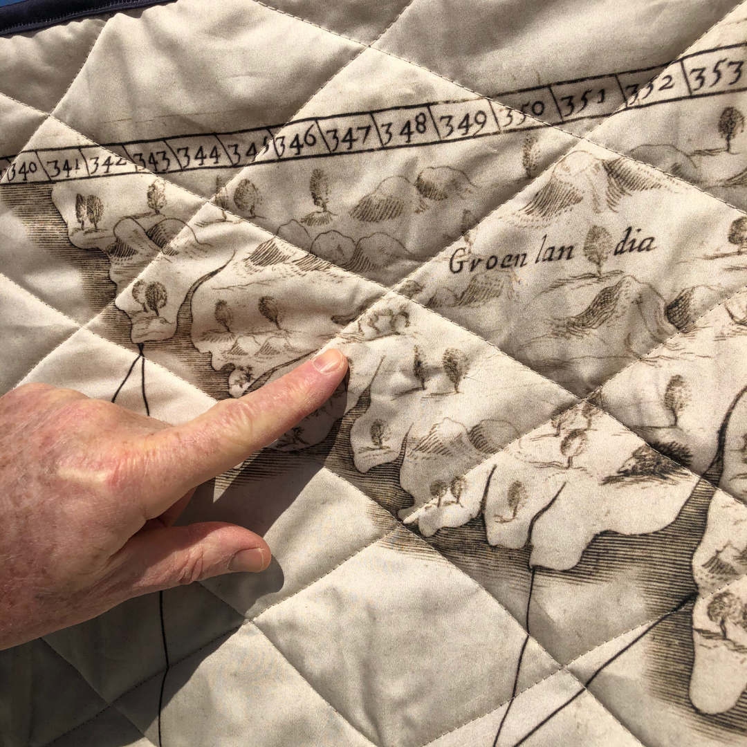 detail of a hand pointing at an enlarged print of a map showing Groenlandia