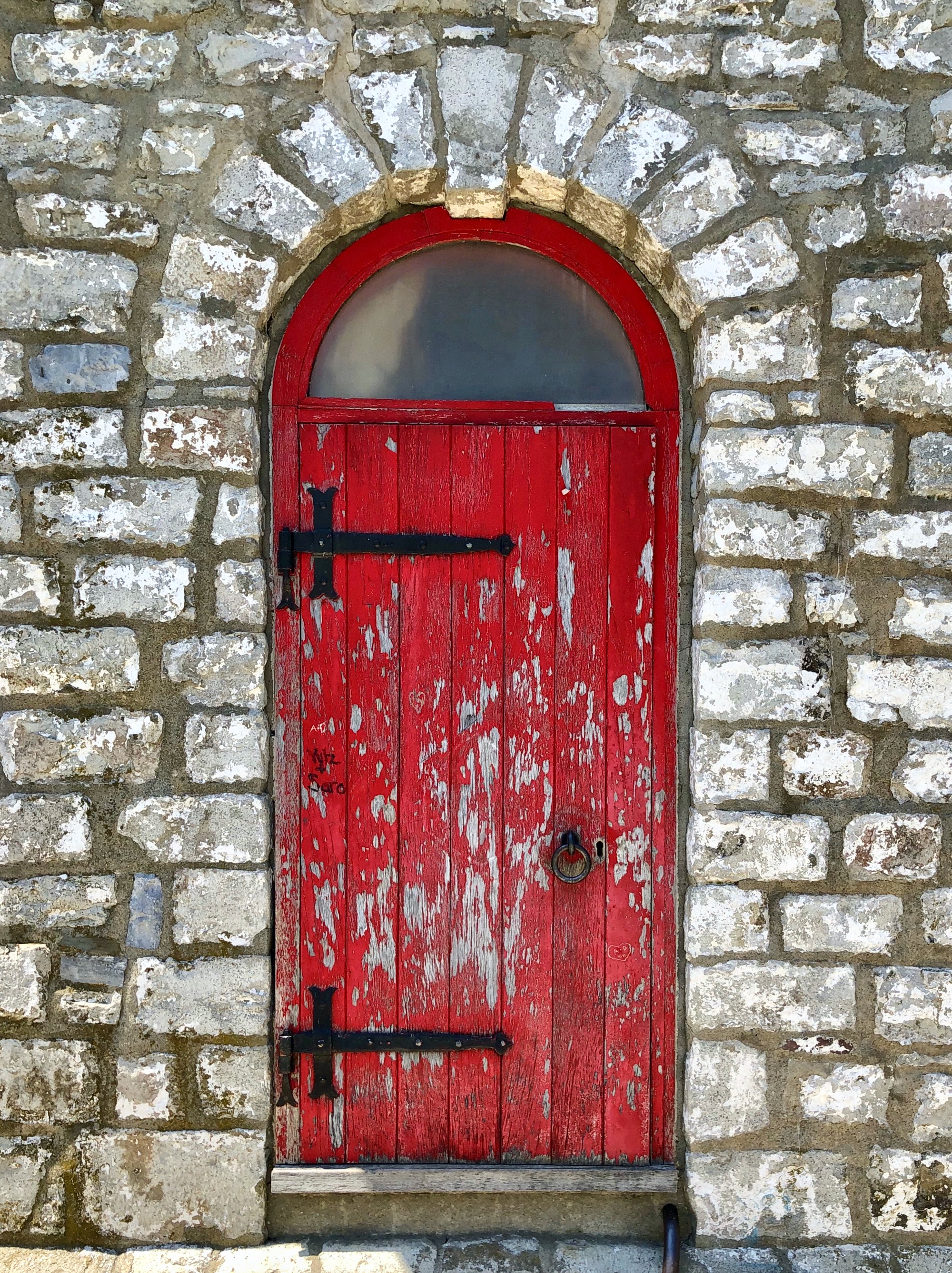 Gros plan de la porte rouge en bois du phare de Gibraltar Point, sur fond de mur en pierre.