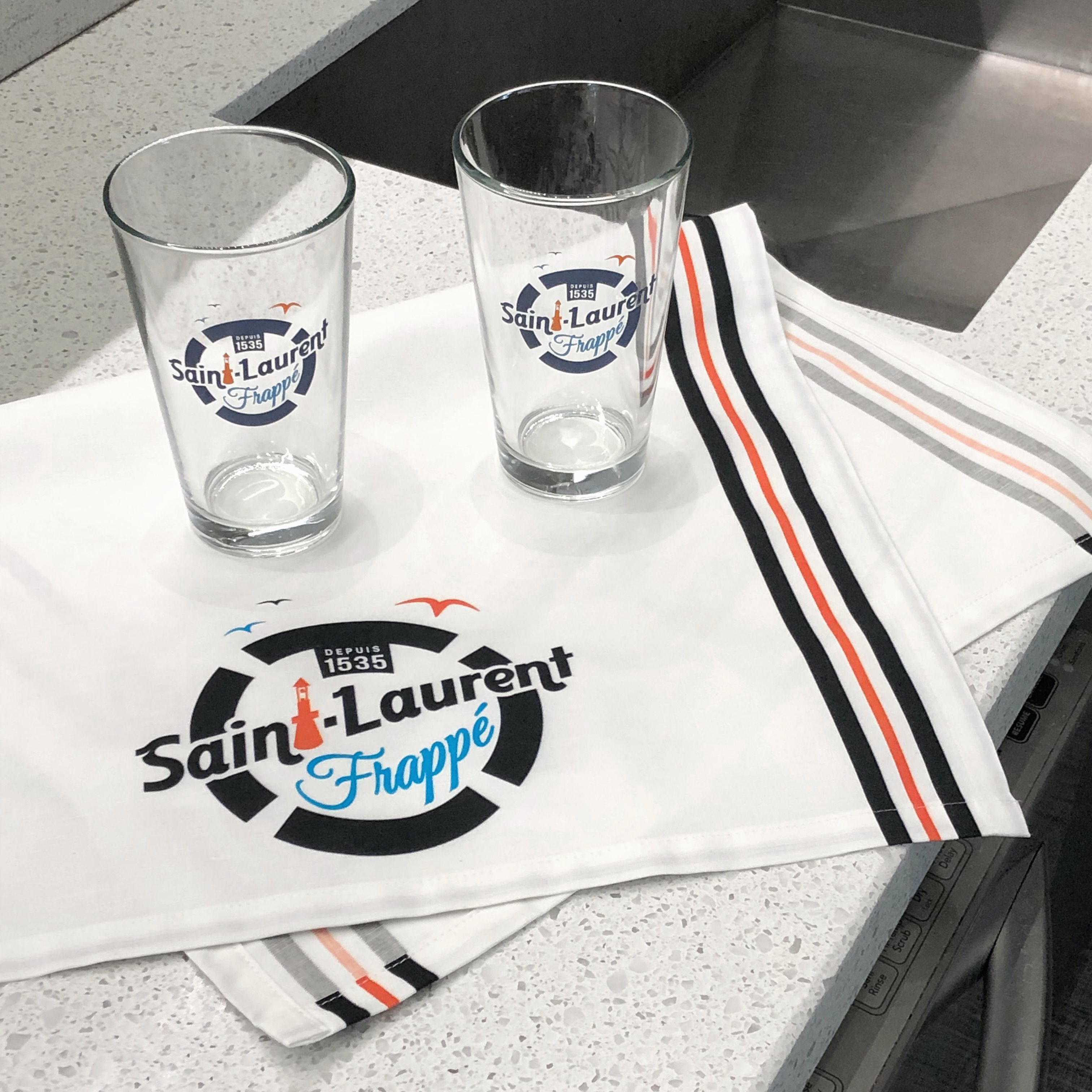 Deux verres à eau et linge à vaisselle avec logo "Saint-Laurent Frappé"